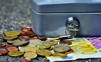 Купюры и монеты возле закрытой коробки, иллюстративное фото