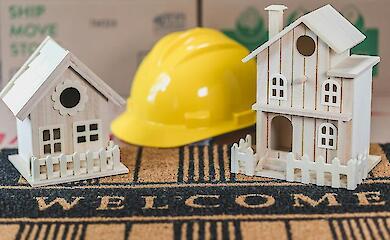 Деревянные миниатюрные домики на коврике с табличкой «Добро пожаловать»