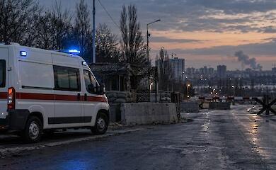 Машина скорой помощи остановилась у перекрытой дороги на фоне далекого дыма